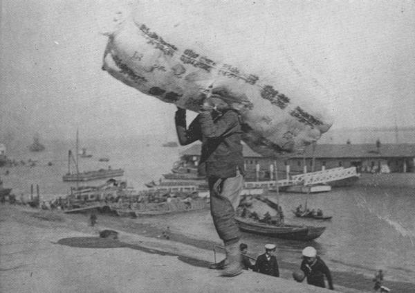 EARNING HIS LIVING

This coolie, who carries 420-lb. bale of cotton, as seen in the picture,
from the ship in the river to the Hankow Bund, probably earns a dollar
and a half per week!