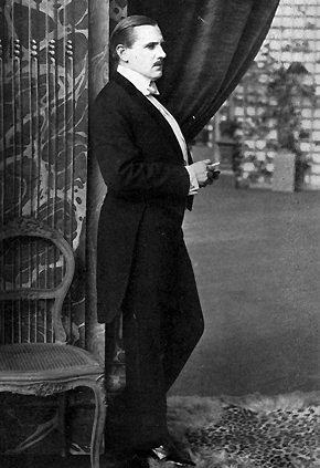 A dapper mustached man in formal dress.